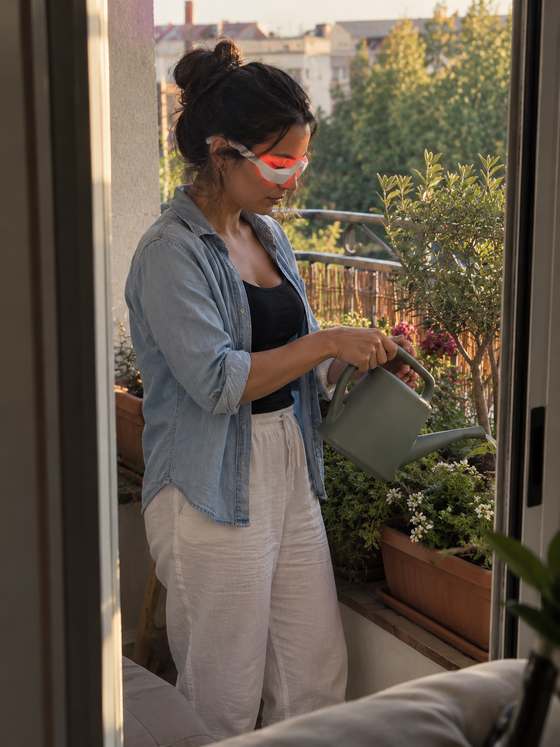 Cliente che annaffia le piante sul balcone con LumiEyes indossato